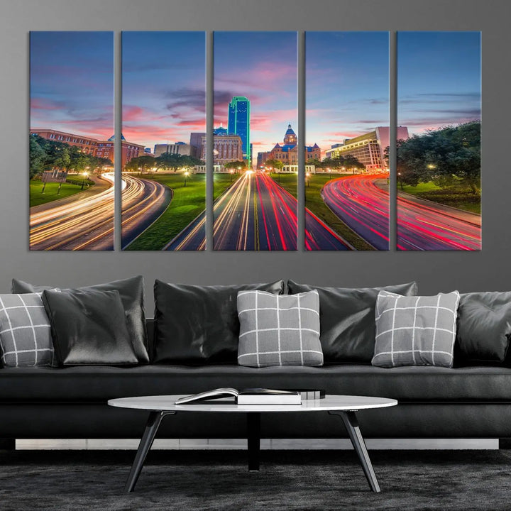 A modern living room features a cityscape triptych wall art titled "Dallas City Street Lights Sunset Pink Cloudy Skyline Cityscape View," printed on museum-quality canvas. It captures a vibrant evening skyline with light trails.