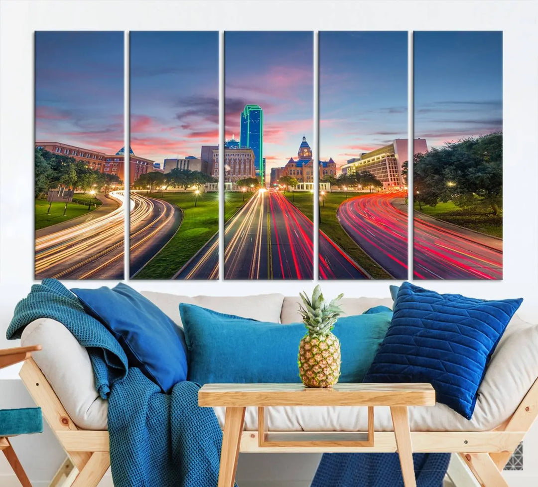 A modern living room features a cityscape triptych wall art titled "Dallas City Street Lights Sunset Pink Cloudy Skyline Cityscape View," printed on museum-quality canvas. It captures a vibrant evening skyline with light trails.