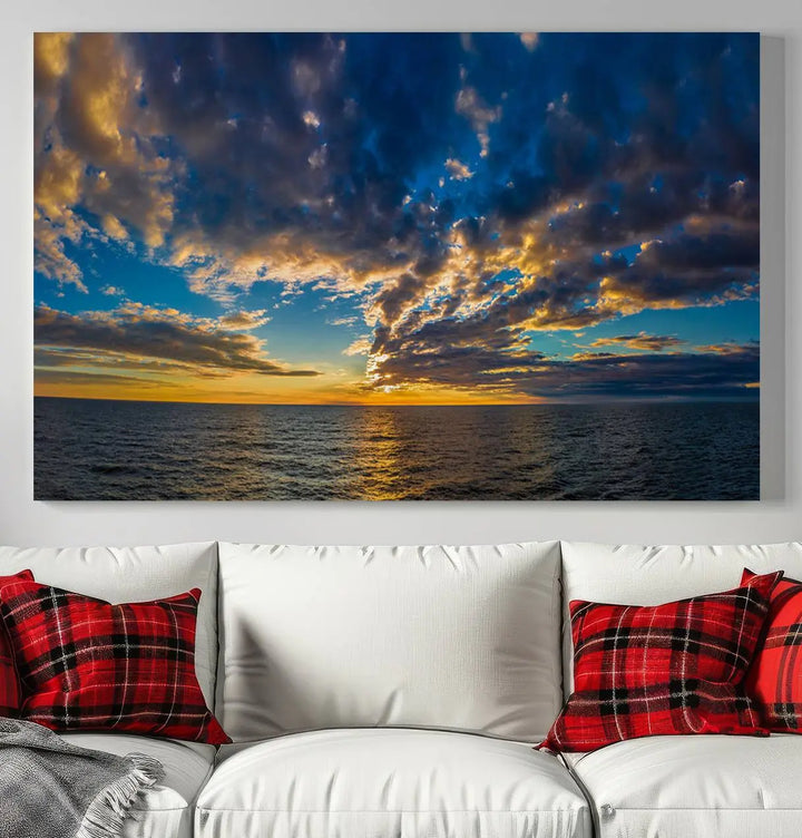 In a cozy living room, the Dark Clouds on the Ocean Beach Sunset Wall Art Canvas Print, featuring three panels and a museum-quality finish, hangs prominently.