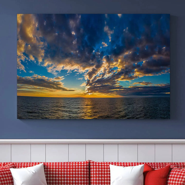 In a cozy living room, the Dark Clouds on the Ocean Beach Sunset Wall Art Canvas Print, featuring three panels and a museum-quality finish, hangs prominently.