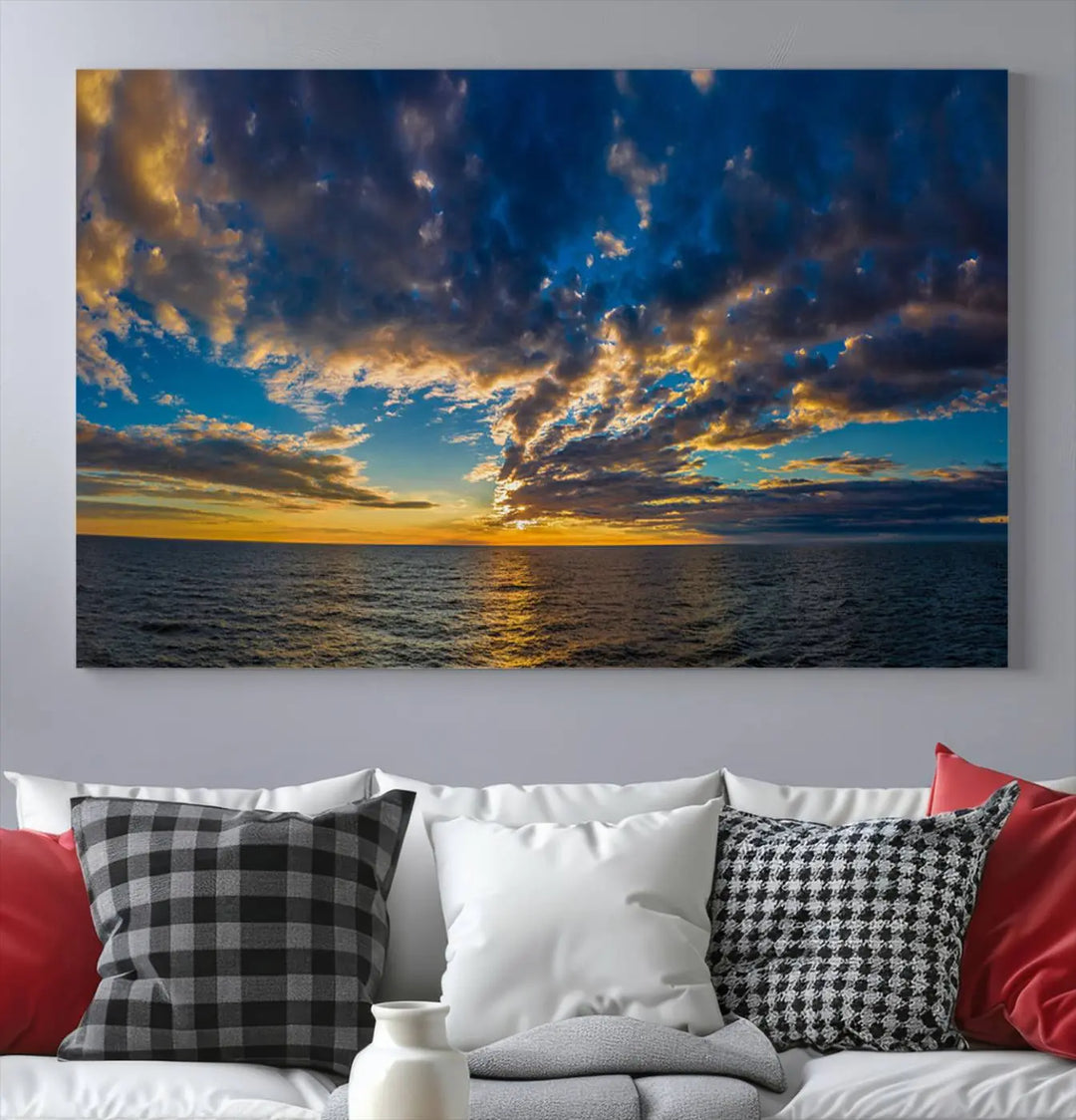 In a cozy living room, the Dark Clouds on the Ocean Beach Sunset Wall Art Canvas Print, featuring three panels and a museum-quality finish, hangs prominently.