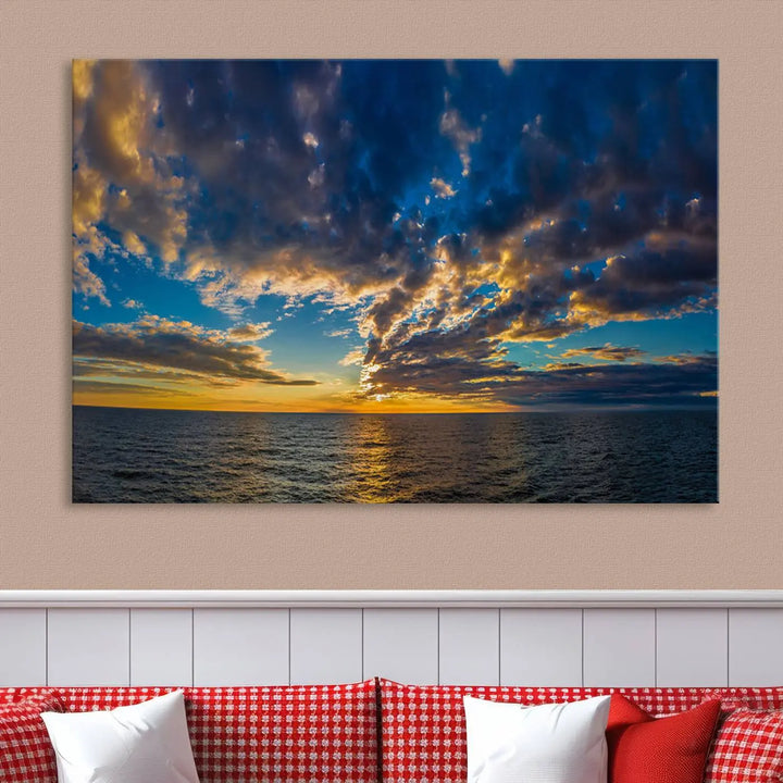 In a cozy living room, the Dark Clouds on the Ocean Beach Sunset Wall Art Canvas Print, featuring three panels and a museum-quality finish, hangs prominently.