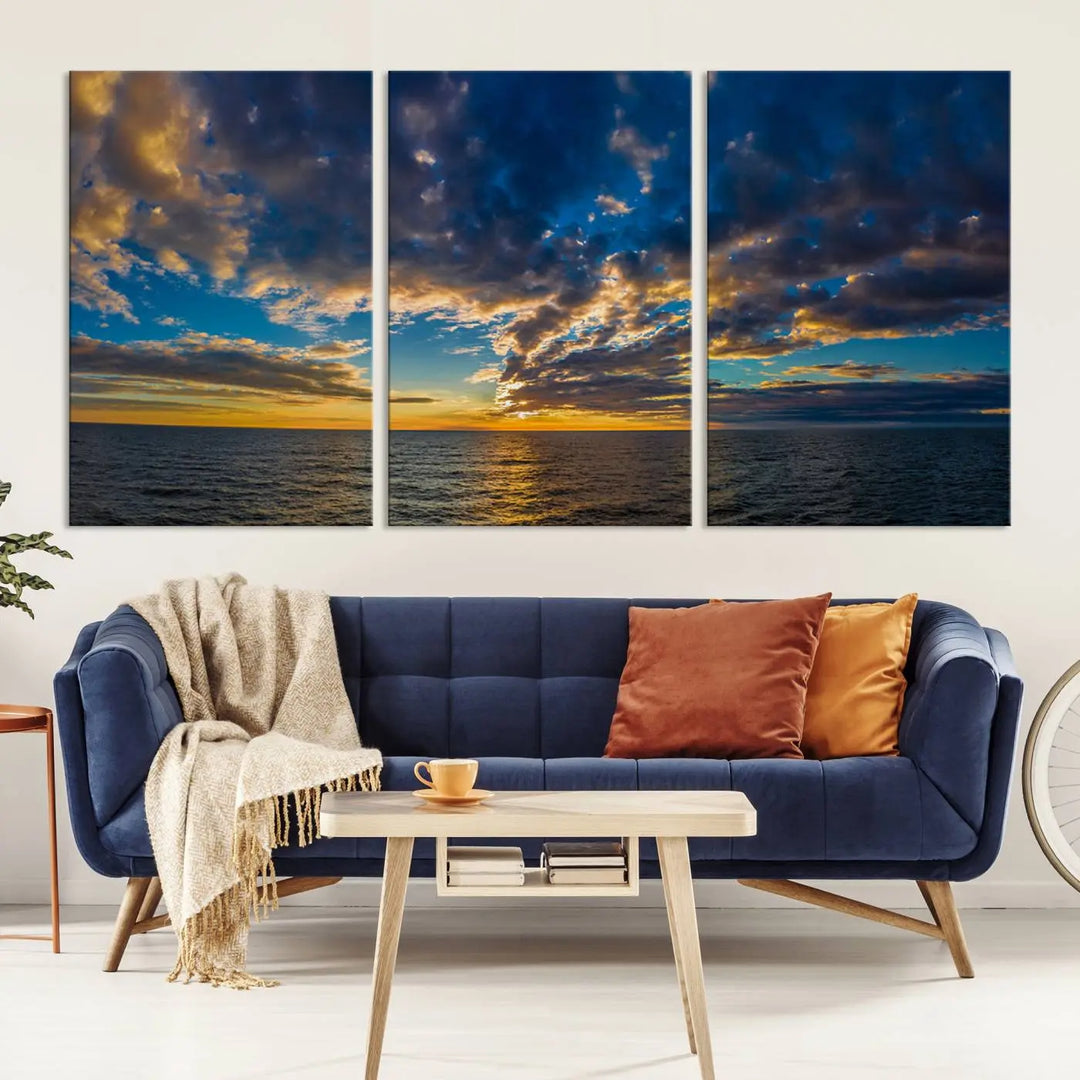 In a cozy living room, the Dark Clouds on the Ocean Beach Sunset Wall Art Canvas Print, featuring three panels and a museum-quality finish, hangs prominently.