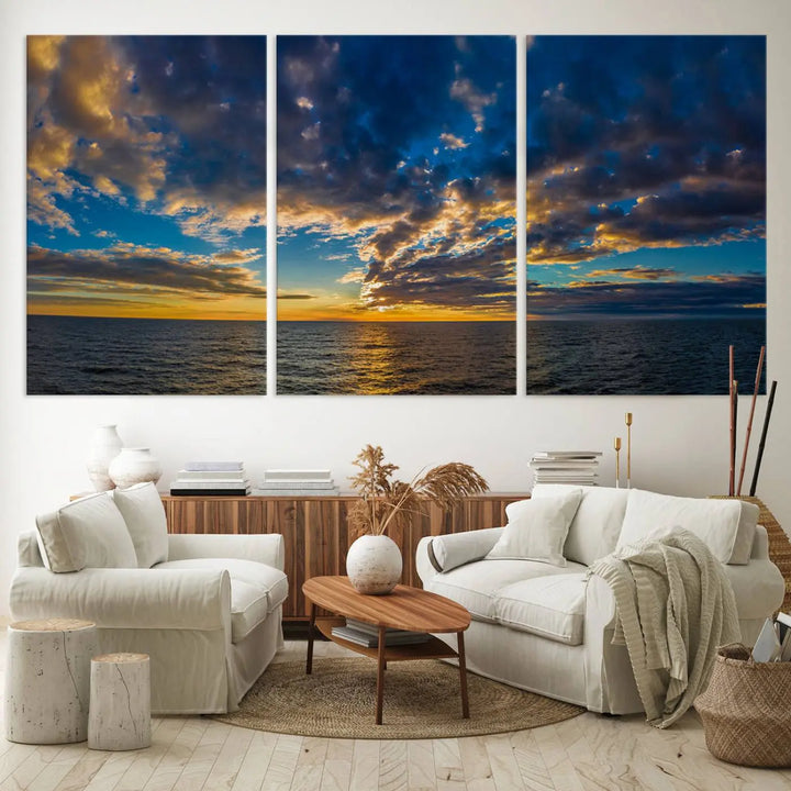 In a cozy living room, the Dark Clouds on the Ocean Beach Sunset Wall Art Canvas Print, featuring three panels and a museum-quality finish, hangs prominently.