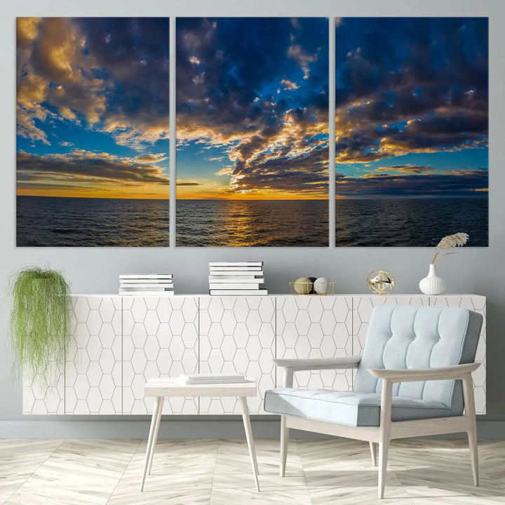 In a cozy living room, the Dark Clouds on the Ocean Beach Sunset Wall Art Canvas Print, featuring three panels and a museum-quality finish, hangs prominently.