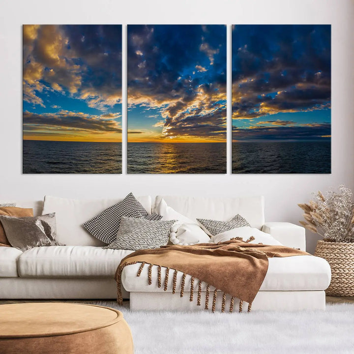 In a cozy living room, the Dark Clouds on the Ocean Beach Sunset Wall Art Canvas Print, featuring three panels and a museum-quality finish, hangs prominently.