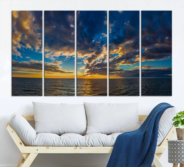 In a cozy living room, the Dark Clouds on the Ocean Beach Sunset Wall Art Canvas Print, featuring three panels and a museum-quality finish, hangs prominently.