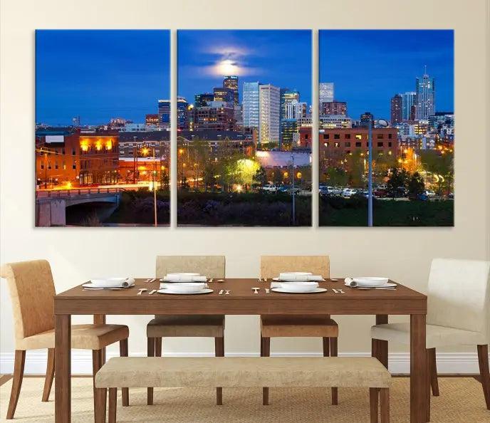 A triptych of the "Denver City Lights Night Blue Skyline Cityscape View" wall art canvas print enhances a modern living room. Crafted on museum-quality canvas with a UV-protective coating, this artwork is ready to hang and effortlessly elevate your space.