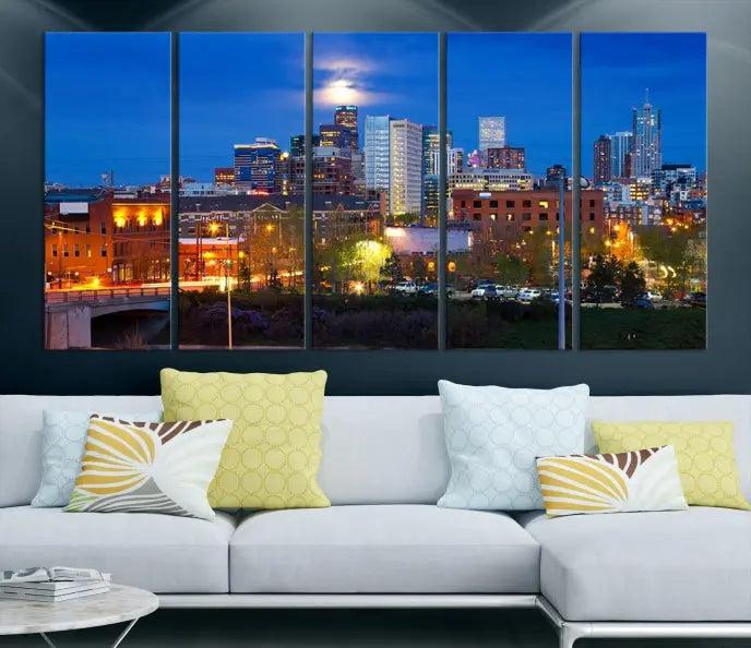 A triptych of the "Denver City Lights Night Blue Skyline Cityscape View" wall art canvas print enhances a modern living room. Crafted on museum-quality canvas with a UV-protective coating, this artwork is ready to hang and effortlessly elevate your space.