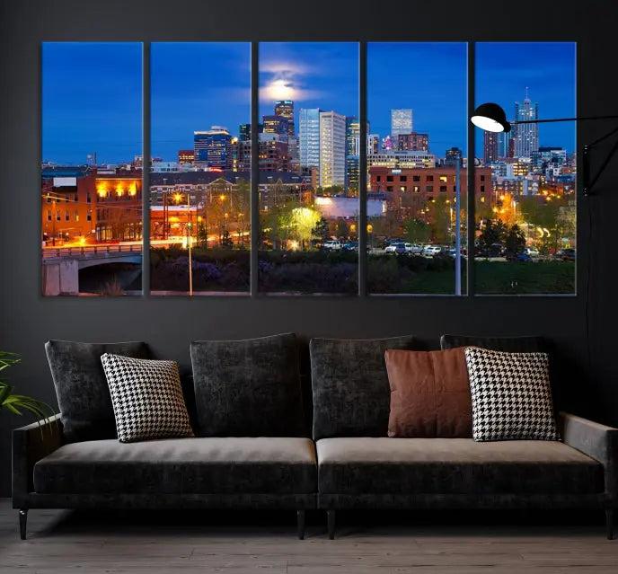 A triptych of the "Denver City Lights Night Blue Skyline Cityscape View" wall art canvas print enhances a modern living room. Crafted on museum-quality canvas with a UV-protective coating, this artwork is ready to hang and effortlessly elevate your space.