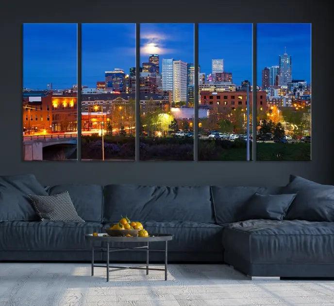 A triptych of the "Denver City Lights Night Blue Skyline Cityscape View" wall art canvas print enhances a modern living room. Crafted on museum-quality canvas with a UV-protective coating, this artwork is ready to hang and effortlessly elevate your space.