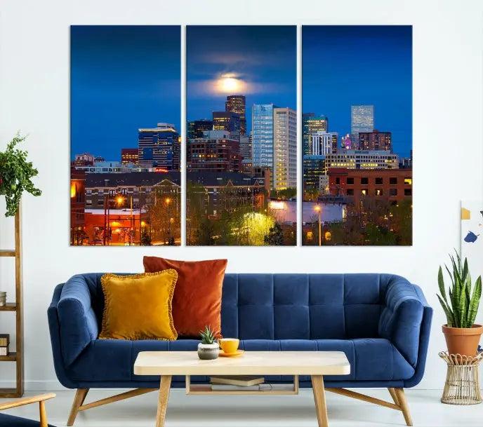 The Denver City Lights Night Blue Skyline Cityscape View Wall Art Canvas Print captures a stunning skyline at night with illuminated buildings and a bright moon, presented on gallery-quality canvas for an elegant display.