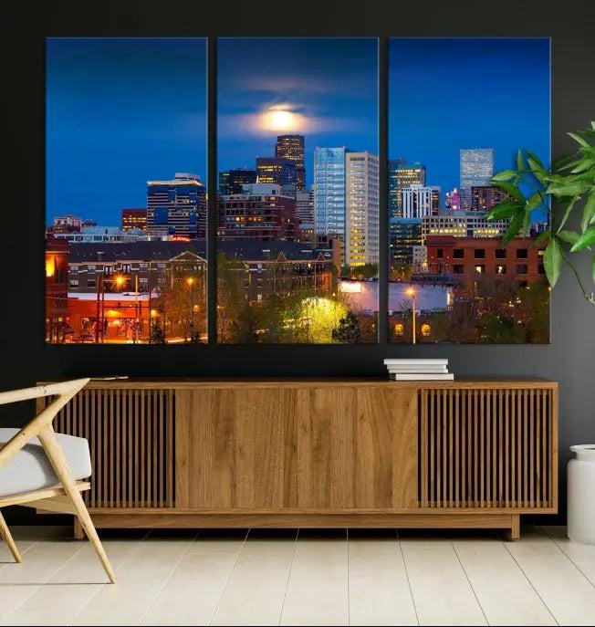 The Denver City Lights Night Blue Skyline Cityscape View Wall Art Canvas Print captures a stunning skyline at night with illuminated buildings and a bright moon, presented on gallery-quality canvas for an elegant display.