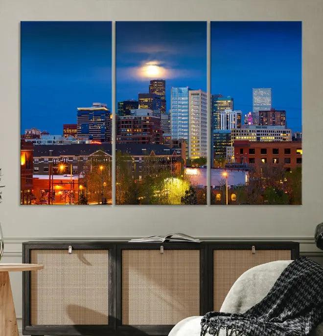 The Denver City Lights Night Blue Skyline Cityscape View Wall Art Canvas Print captures a stunning skyline at night with illuminated buildings and a bright moon, presented on gallery-quality canvas for an elegant display.