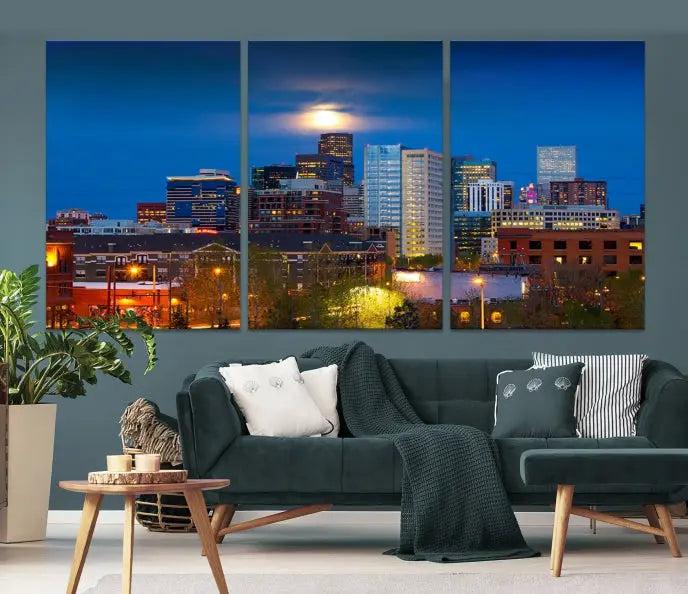 The Denver City Lights Night Blue Skyline Cityscape View Wall Art Canvas Print captures a stunning skyline at night with illuminated buildings and a bright moon, presented on gallery-quality canvas for an elegant display.