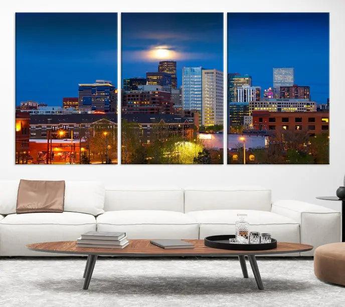 The Denver City Lights Night Blue Skyline Cityscape View Wall Art Canvas Print captures a stunning skyline at night with illuminated buildings and a bright moon, presented on gallery-quality canvas for an elegant display.