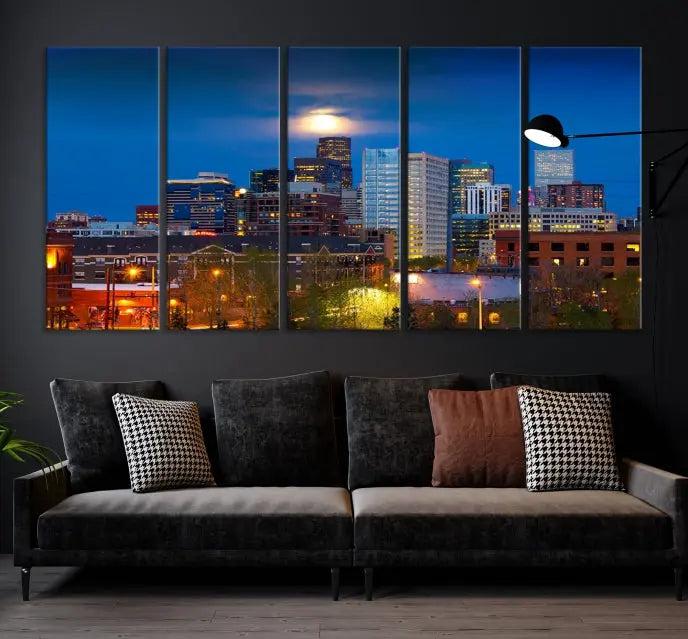 The Denver City Lights Night Blue Skyline Cityscape View Wall Art Canvas Print captures a stunning skyline at night with illuminated buildings and a bright moon, presented on gallery-quality canvas for an elegant display.