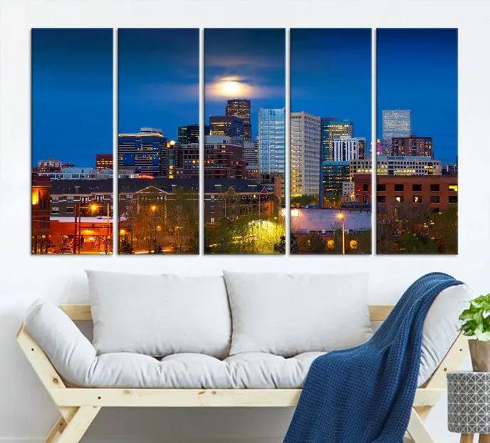 The Denver City Lights Night Blue Skyline Cityscape View Wall Art Canvas Print captures a stunning skyline at night with illuminated buildings and a bright moon, presented on gallery-quality canvas for an elegant display.