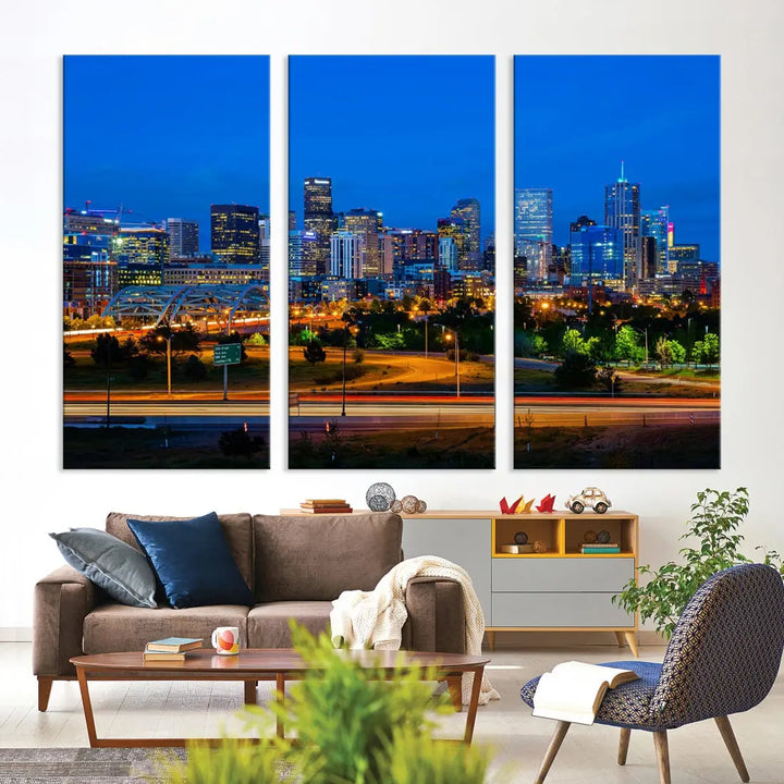 A modern living room showcases the "Denver City Lights Night Blue Skyline Cityscape View Wall Art Canvas Print" in a triptych arrangement. These museum-quality canvases, finished with a UV-protective coating, maintain their vibrant allure.