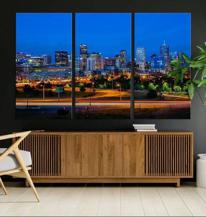 A modern living room showcases the "Denver City Lights Night Blue Skyline Cityscape View Wall Art Canvas Print" in a triptych arrangement. These museum-quality canvases, finished with a UV-protective coating, maintain their vibrant allure.