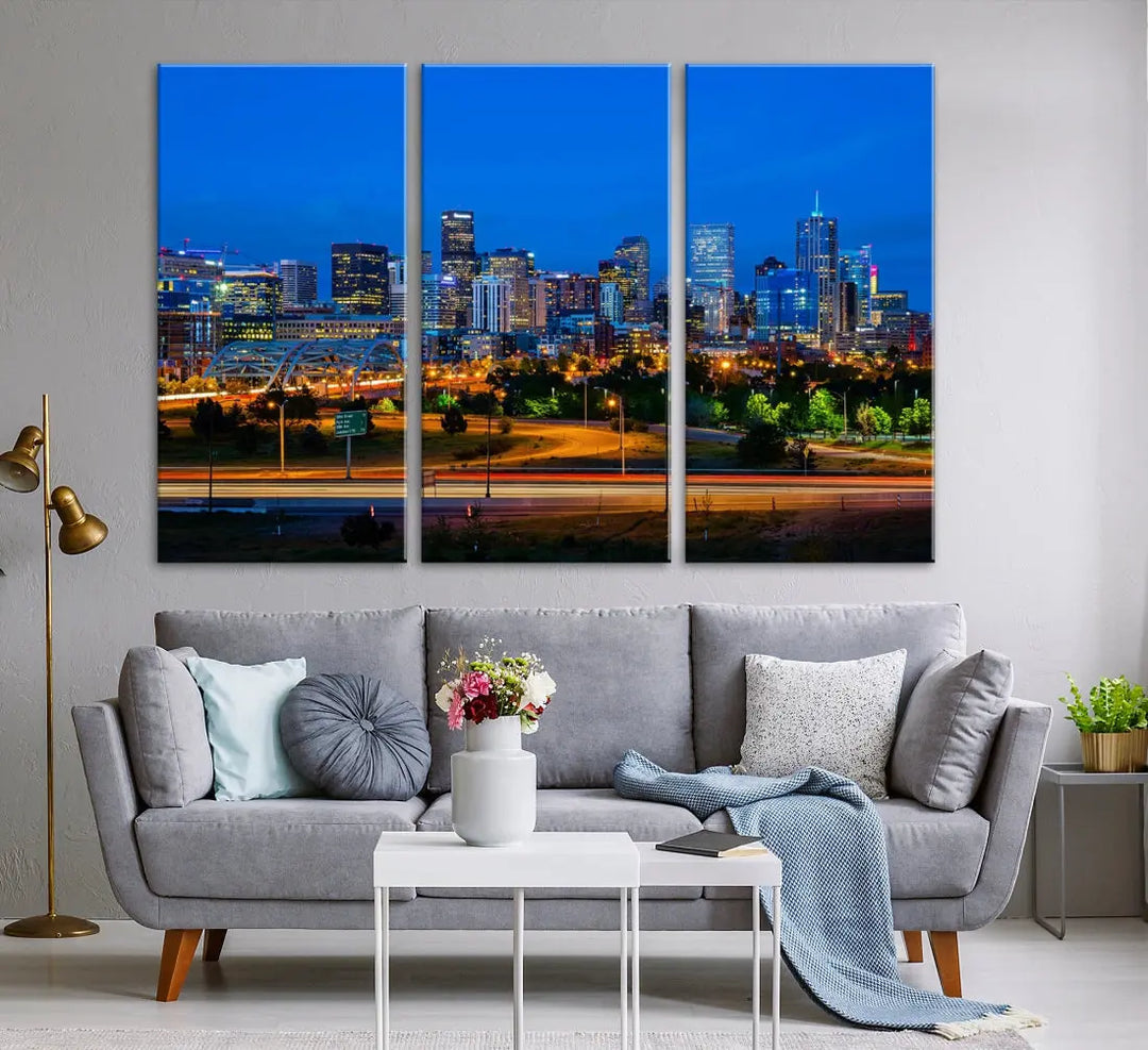 A modern living room showcases the "Denver City Lights Night Blue Skyline Cityscape View Wall Art Canvas Print" in a triptych arrangement. These museum-quality canvases, finished with a UV-protective coating, maintain their vibrant allure.