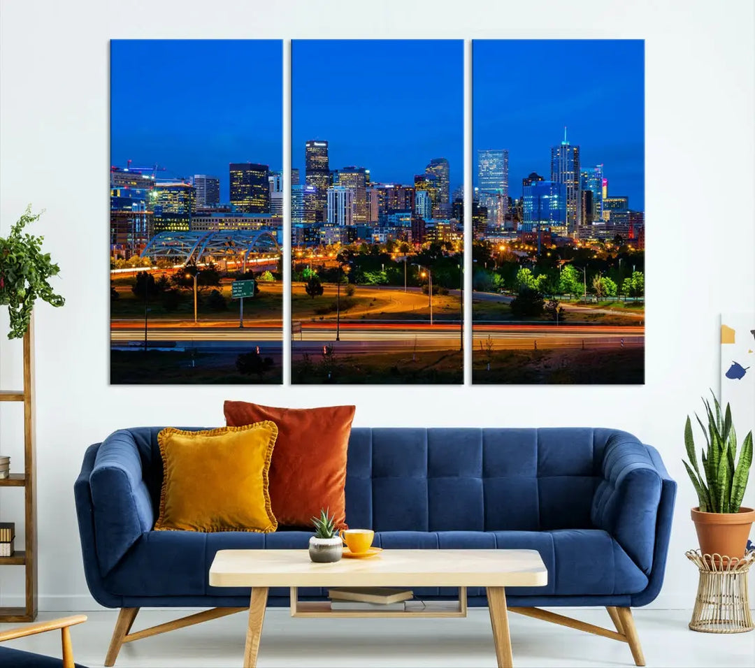 A modern living room showcases the "Denver City Lights Night Blue Skyline Cityscape View Wall Art Canvas Print" in a triptych arrangement. These museum-quality canvases, finished with a UV-protective coating, maintain their vibrant allure.