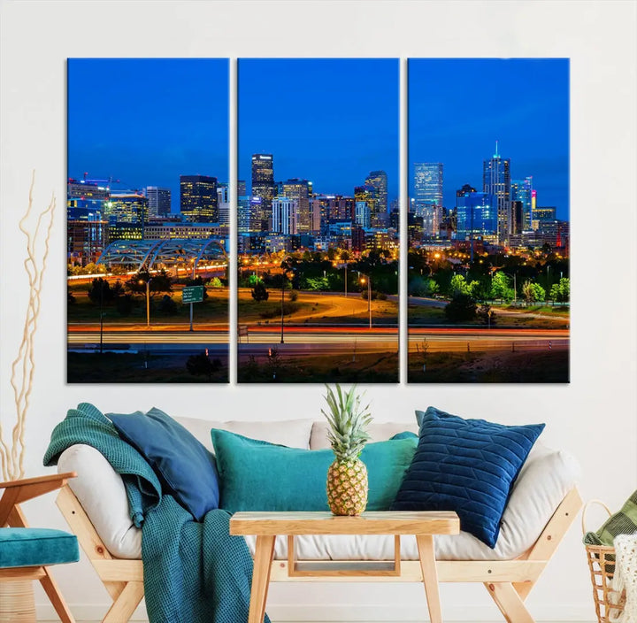 A modern living room showcases the "Denver City Lights Night Blue Skyline Cityscape View Wall Art Canvas Print" in a triptych arrangement. These museum-quality canvases, finished with a UV-protective coating, maintain their vibrant allure.