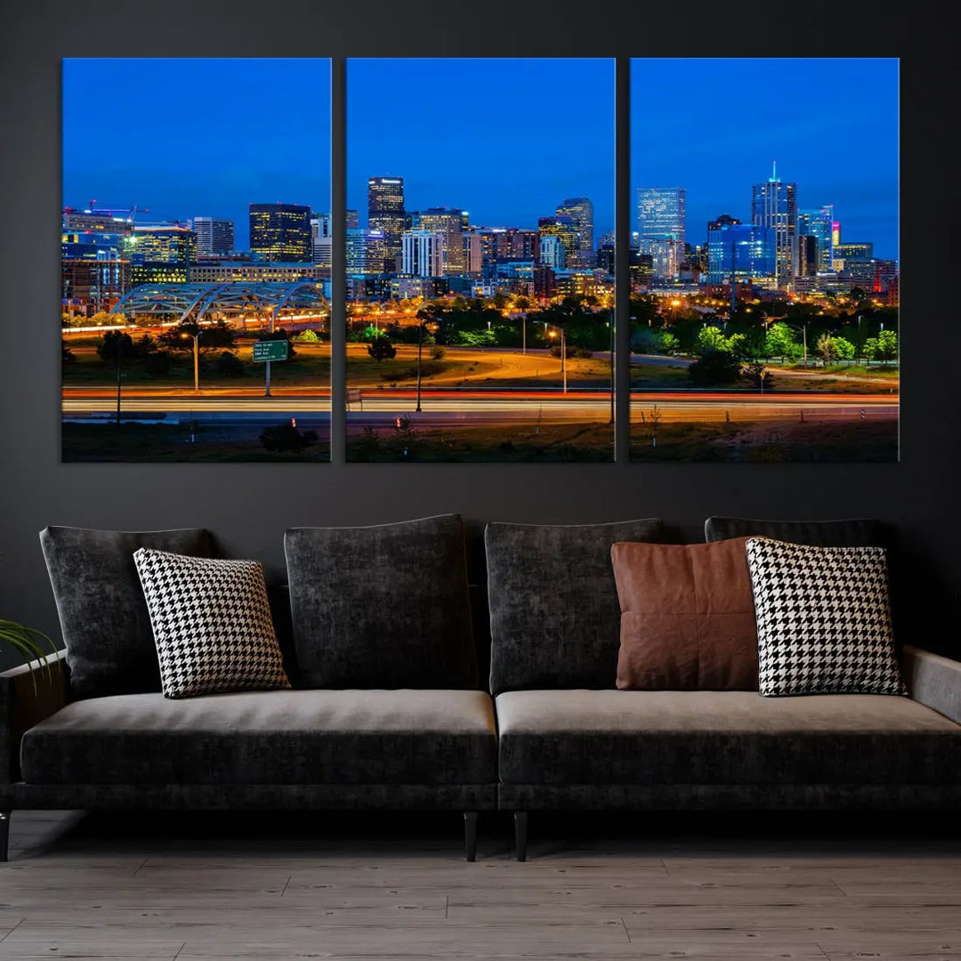 A modern living room showcases the "Denver City Lights Night Blue Skyline Cityscape View Wall Art Canvas Print" in a triptych arrangement. These museum-quality canvases, finished with a UV-protective coating, maintain their vibrant allure.