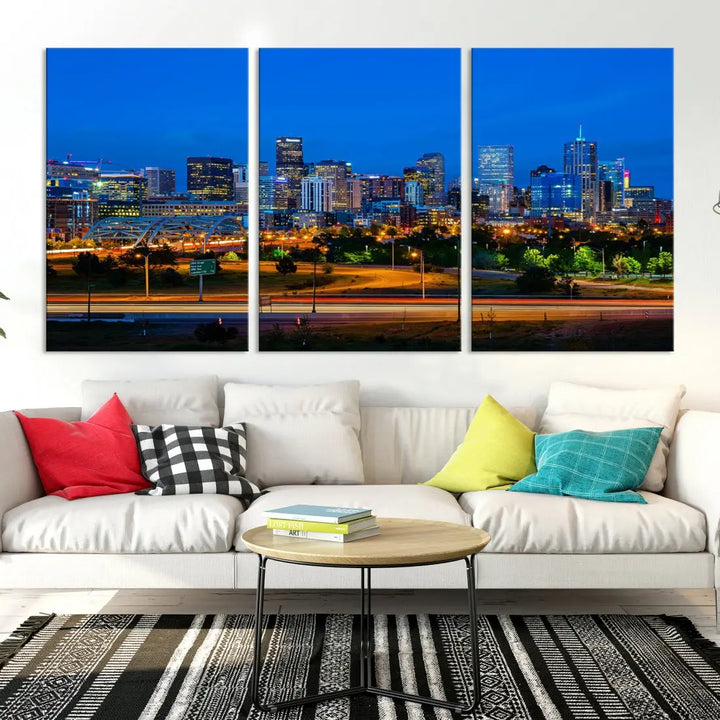 A modern living room showcases the "Denver City Lights Night Blue Skyline Cityscape View Wall Art Canvas Print" in a triptych arrangement. These museum-quality canvases, finished with a UV-protective coating, maintain their vibrant allure.