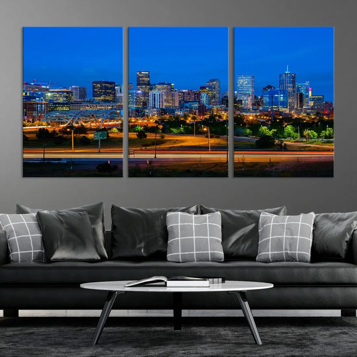 A modern living room showcases the "Denver City Lights Night Blue Skyline Cityscape View Wall Art Canvas Print" in a triptych arrangement. These museum-quality canvases, finished with a UV-protective coating, maintain their vibrant allure.