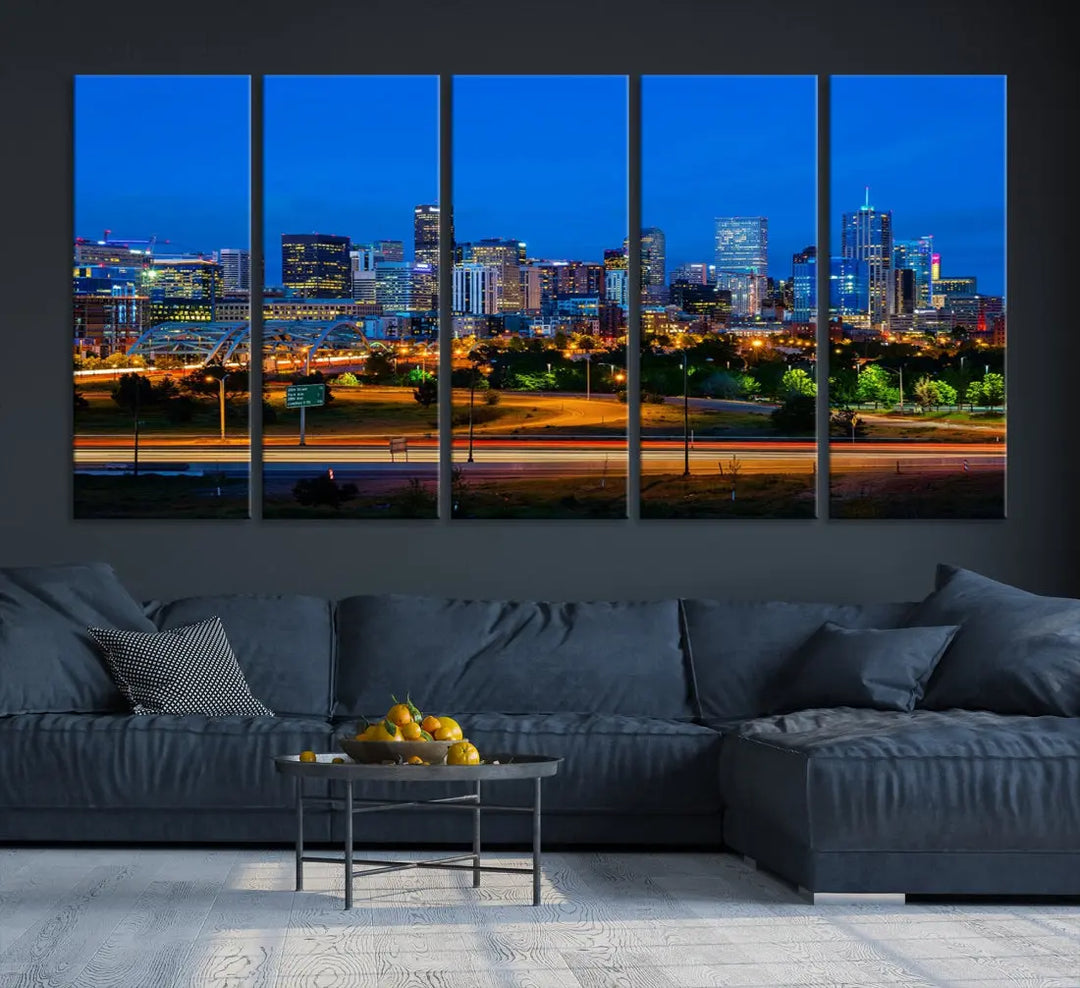 A modern living room showcases the "Denver City Lights Night Blue Skyline Cityscape View Wall Art Canvas Print" in a triptych arrangement. These museum-quality canvases, finished with a UV-protective coating, maintain their vibrant allure.