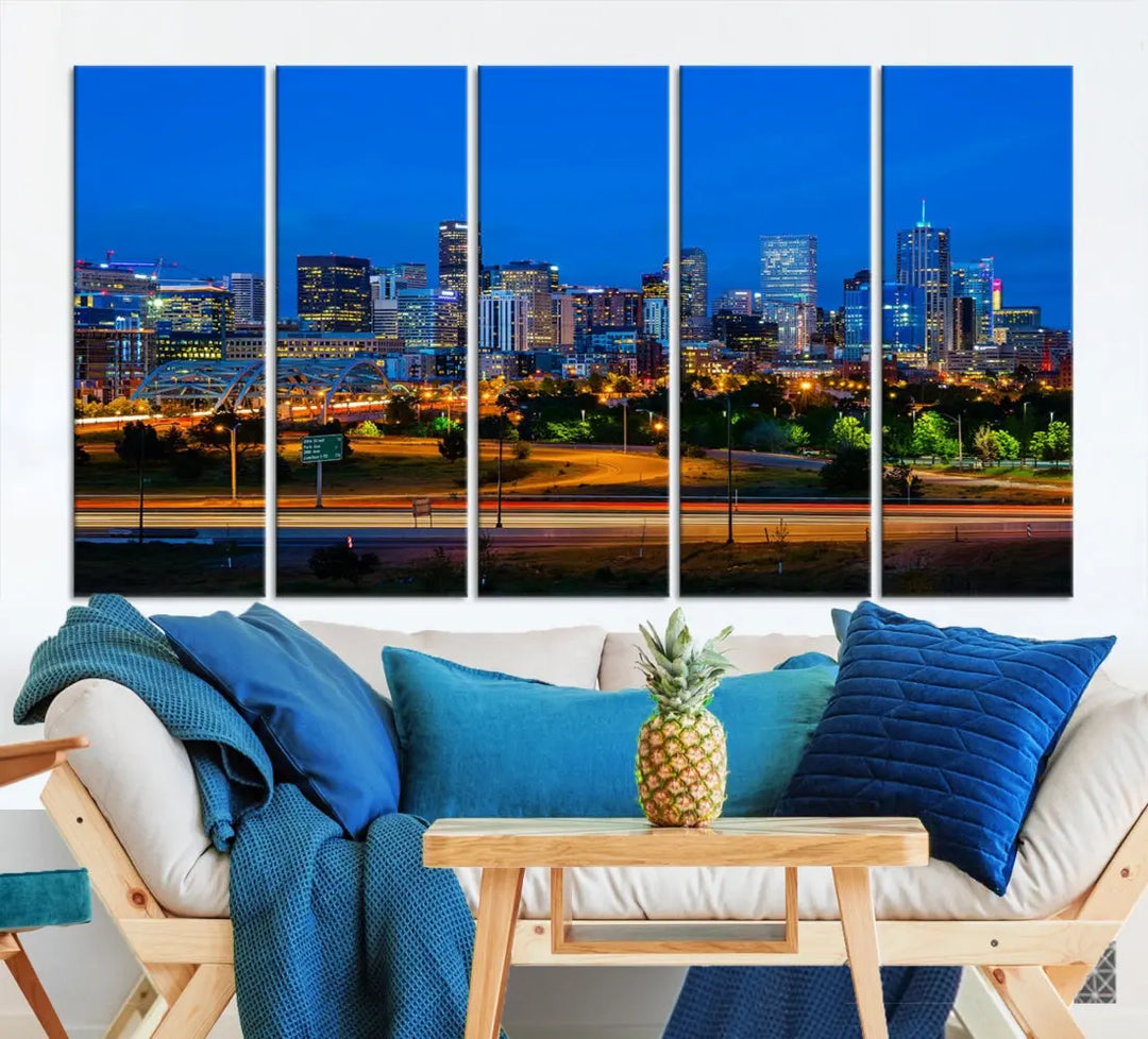 A modern living room showcases the "Denver City Lights Night Blue Skyline Cityscape View Wall Art Canvas Print" in a triptych arrangement. These museum-quality canvases, finished with a UV-protective coating, maintain their vibrant allure.