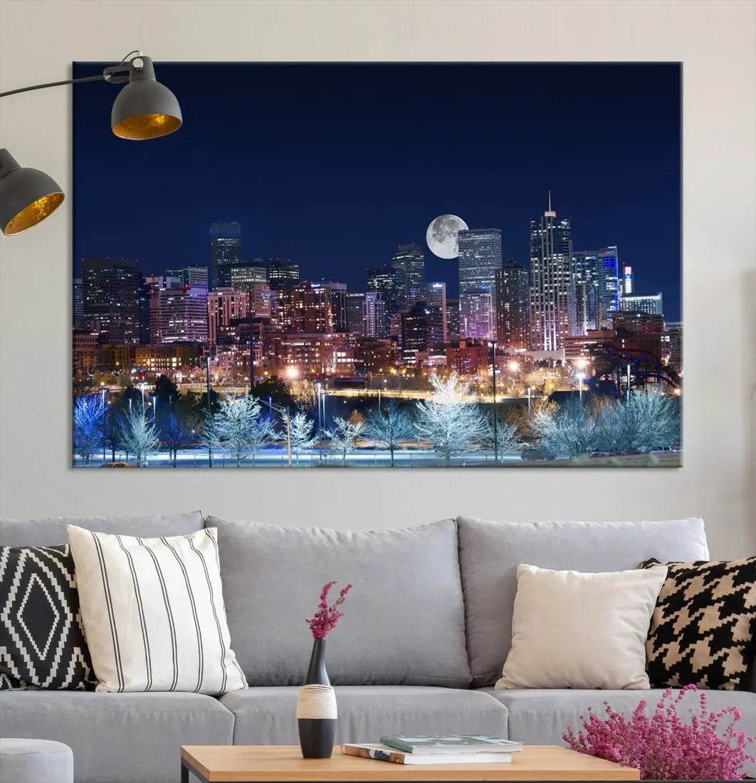 A cozy living room features the "Denver City Lights Night with Full Moon Skyline Cityscape View" wall art canvas print, gallery wrapped on museum-quality canvas.