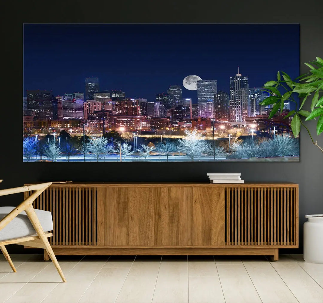 A cozy living room features the "Denver City Lights Night with Full Moon Skyline Cityscape View" wall art canvas print, gallery wrapped on museum-quality canvas.