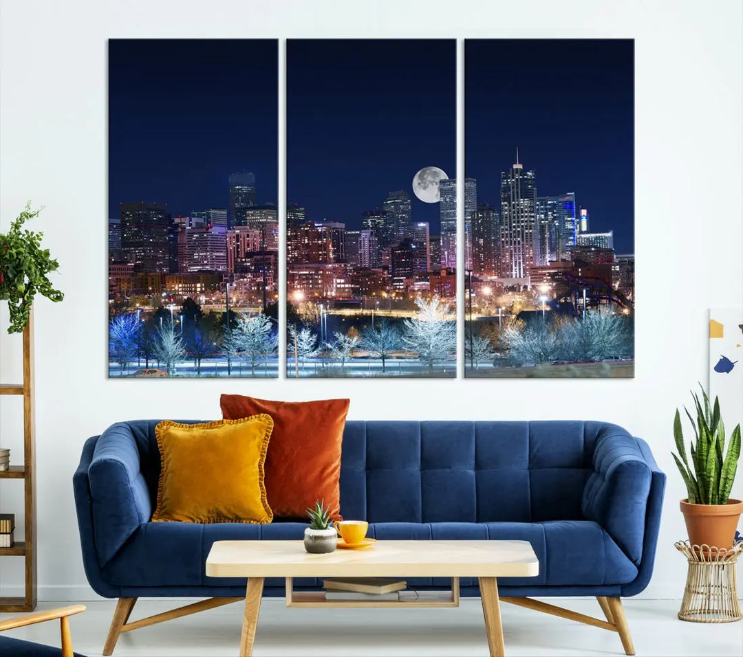 A cozy living room features the "Denver City Lights Night with Full Moon Skyline Cityscape View" wall art canvas print, gallery wrapped on museum-quality canvas.