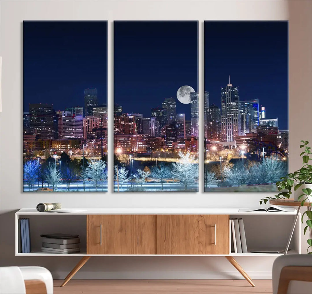 A cozy living room features the "Denver City Lights Night with Full Moon Skyline Cityscape View" wall art canvas print, gallery wrapped on museum-quality canvas.