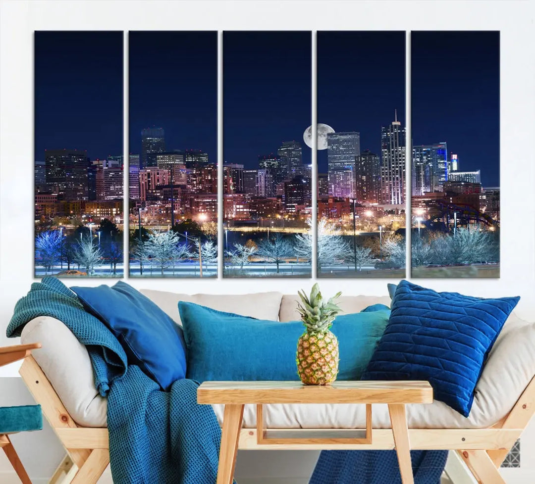 A cozy living room features the "Denver City Lights Night with Full Moon Skyline Cityscape View" wall art canvas print, gallery wrapped on museum-quality canvas.