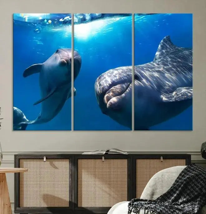 The Dolphin Wall Art Underwater Canvas Print showcases three panels of dolphins swimming underwater, gallery wrapped on museum-quality canvas with UV-protective coating.