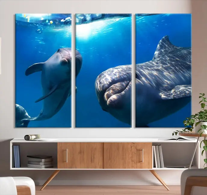 The Dolphin Wall Art Underwater Canvas Print showcases three panels of dolphins swimming underwater, gallery wrapped on museum-quality canvas with UV-protective coating.