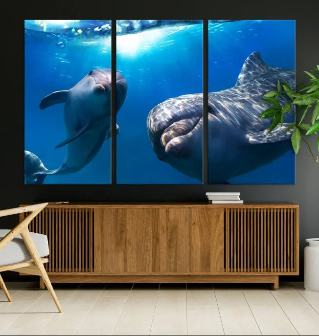 The Dolphin Wall Art Underwater Canvas Print showcases three panels of dolphins swimming underwater, gallery wrapped on museum-quality canvas with UV-protective coating.