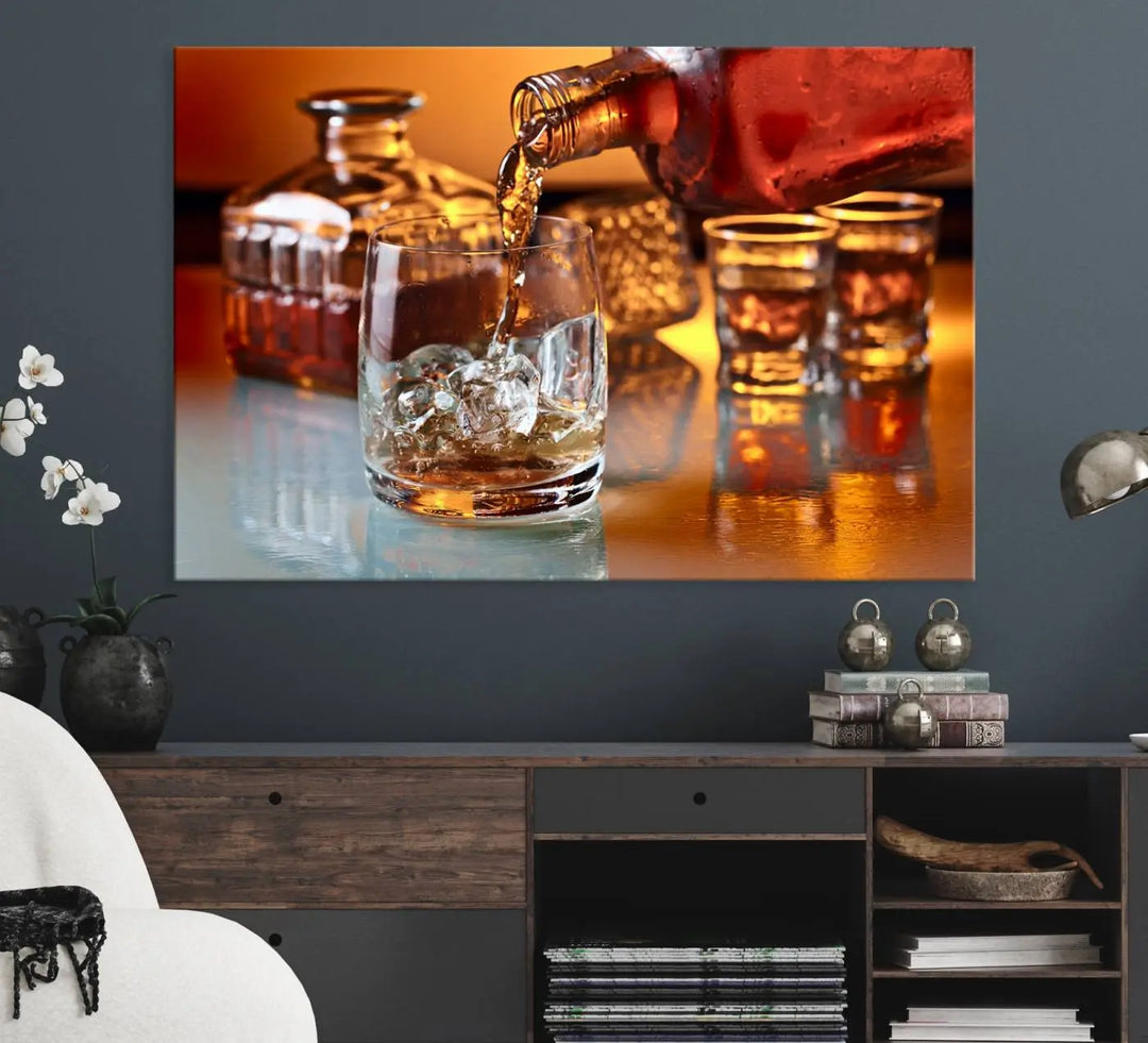 The Elegant Whiskey Canvas Art captures the reflection of a whiskey bottle pouring into an iced glass beside two filled ones.