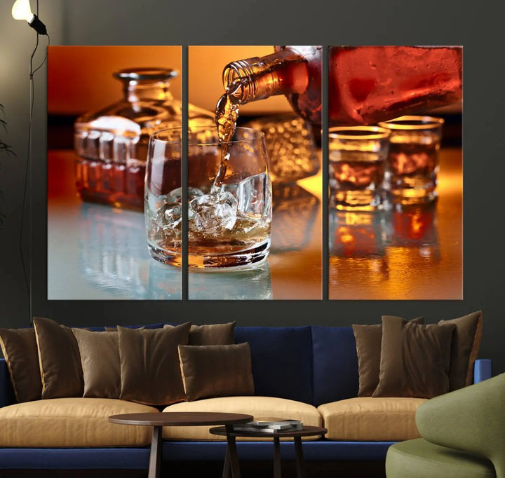 The Elegant Whiskey Canvas Art captures the reflection of a whiskey bottle pouring into an iced glass beside two filled ones.