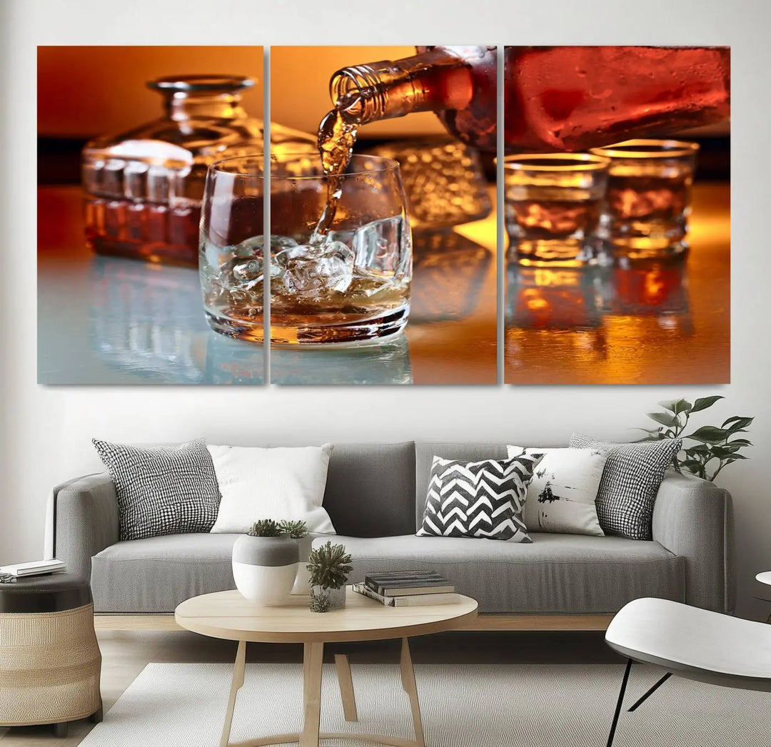 The Elegant Whiskey Canvas Art captures the reflection of a whiskey bottle pouring into an iced glass beside two filled ones.