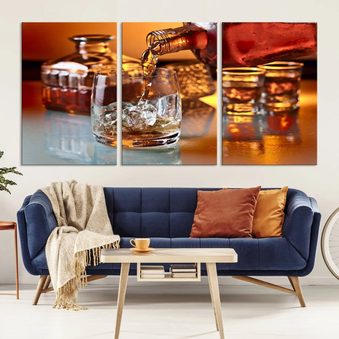 The Elegant Whiskey Canvas Art captures the reflection of a whiskey bottle pouring into an iced glass beside two filled ones.