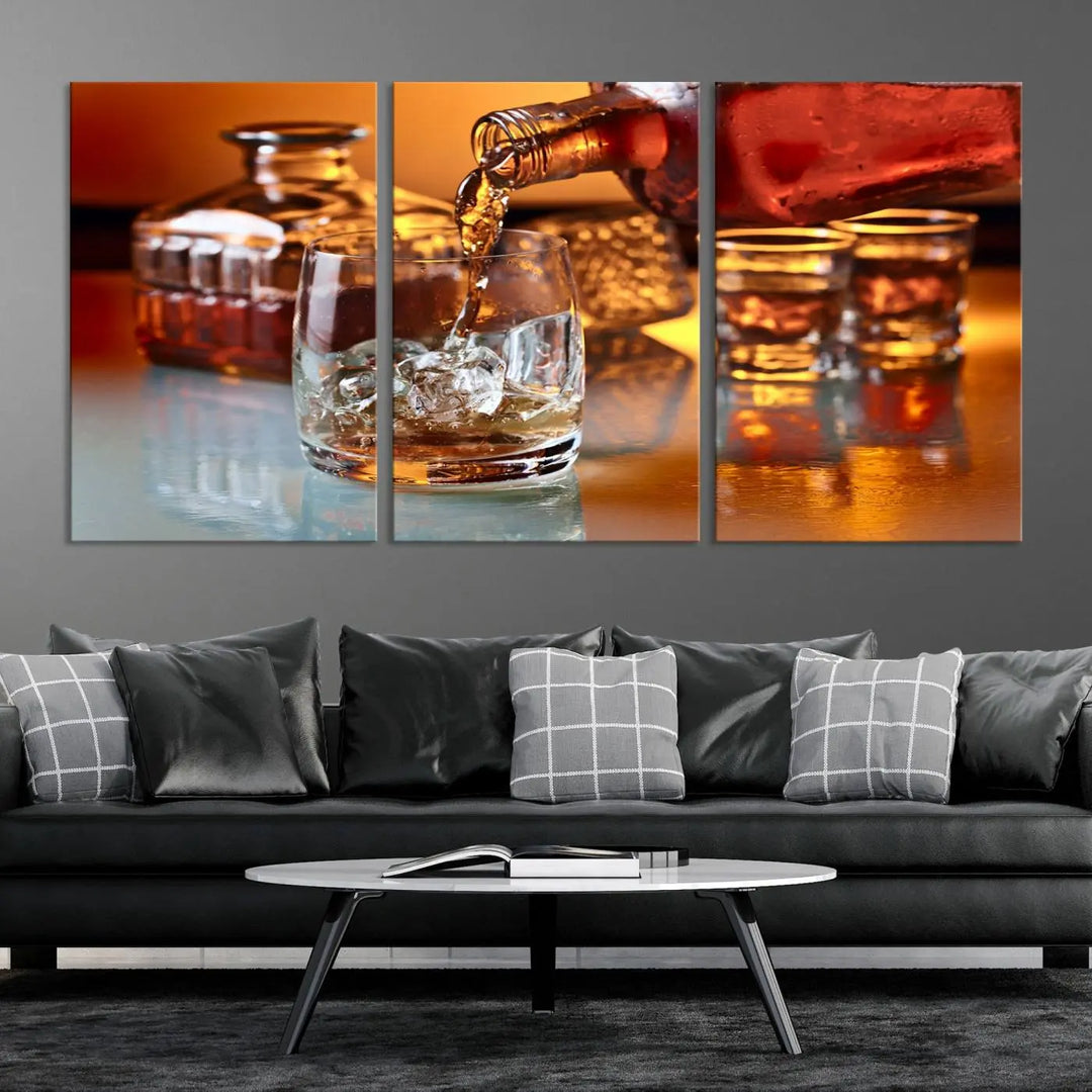 The Elegant Whiskey Canvas Art captures the reflection of a whiskey bottle pouring into an iced glass beside two filled ones.