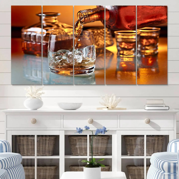 The Elegant Whiskey Canvas Art captures the reflection of a whiskey bottle pouring into an iced glass beside two filled ones.