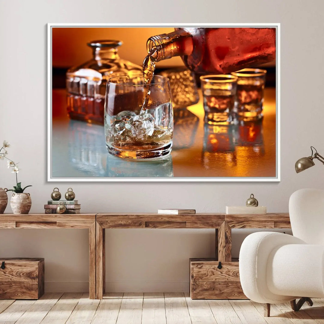 The Elegant Whiskey Canvas Art captures the reflection of a whiskey bottle pouring into an iced glass beside two filled ones.