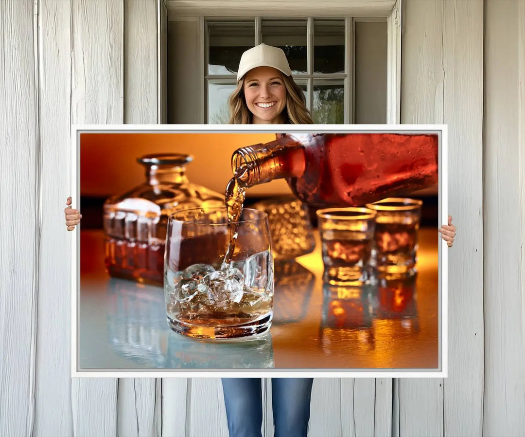 The Elegant Whiskey Canvas Art captures the reflection of a whiskey bottle pouring into an iced glass beside two filled ones.