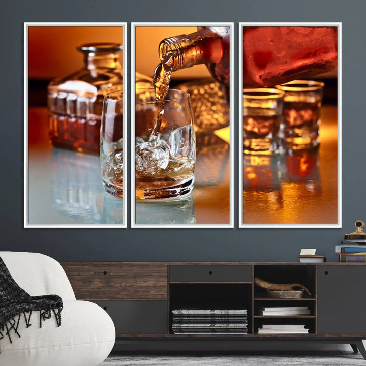 The Elegant Whiskey Canvas Art captures the reflection of a whiskey bottle pouring into an iced glass beside two filled ones.