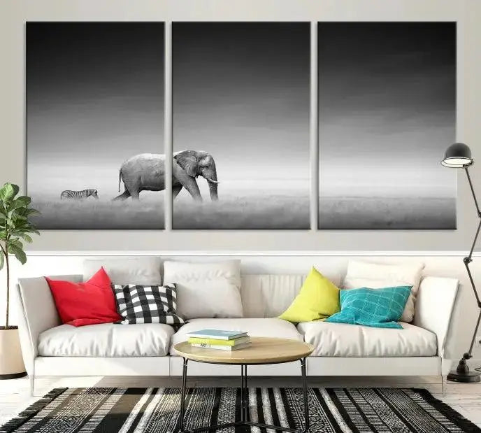 Elephant and Zebra Wall Art Canvas Print: A black and white triptych on museum-quality canvas, showcasing an elephant and zebra walking across a grassy plain. Equipped with a UV-protective coating for lasting protection.